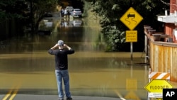 A man photographs a flooded street, Feb. 10, 2017, in Guerneville, Calif. The Russian River rose above its flood stage again Friday. More rain is forecast for the weekend.