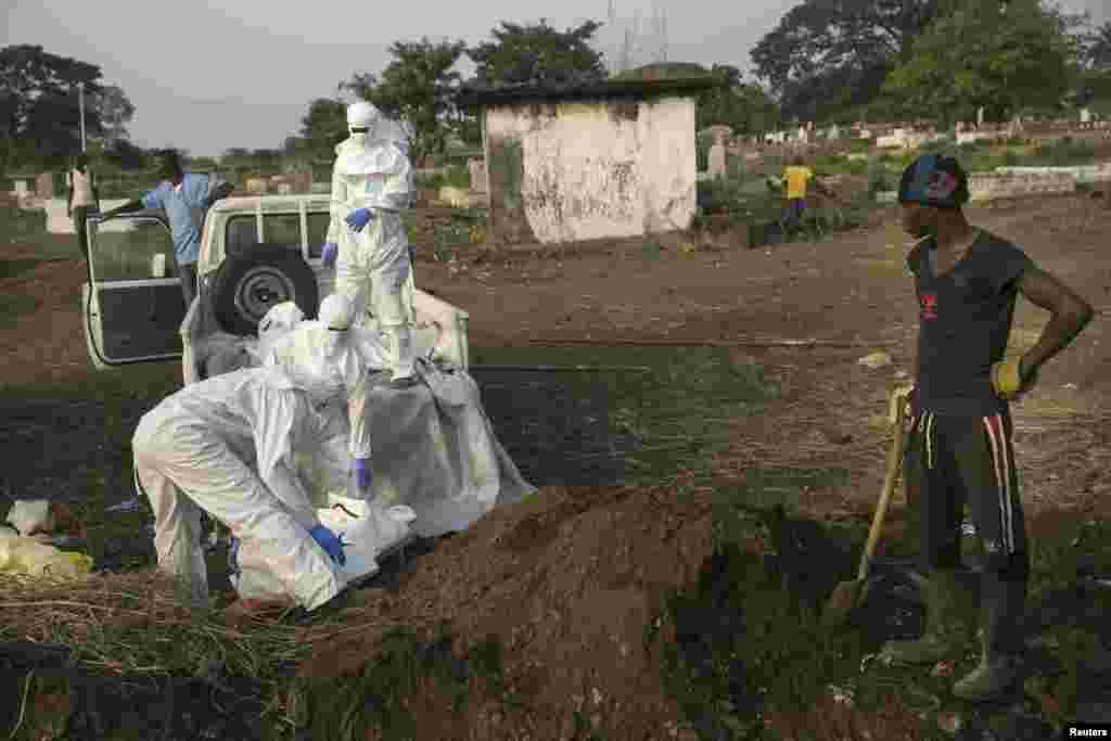Un fossoyeur attend pelle en main pour enterrer le corps d’une victime d’Ebola que le personnel de santé amène à un cimetière à Freetown, 17 décembre 2014. REUTERS / Baz Ratner