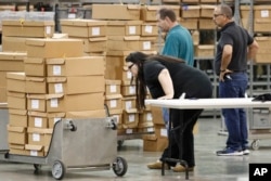 Employees prepare to unpack boxes of ballots before resuming a recount at the Palm Beach County Supervisor of Elections office, Nov. 15, 2018, in West Palm Beach, Florida.