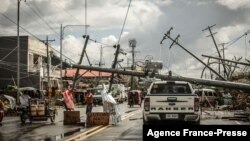 Tiang-tiang lisytrik memblokir jalanan di Surigao City, Filipina utara sementara warga meminta bantuan makanan pasca topan Rai melanda wilayah itu (19/12).