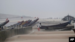 An Indian fisherman walks near the anchored fishing boats as strong winds blow a day after a powerful cyclone pounded the Bay of Bengal coast in Gopalpur, Orissa, about 285 kilometers (178 miles) north east of Visakhapatnam, India, Monday, Oct. 13, 2014.