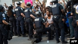 Forte émotion d'un manifestant lorsqu'un un policier met un genou à terre en signe de solidarité lors d'une manifestation contre la mort de George Floyd à côté de la Maison Blanche le 31 mai 2020 à Washington, DC.