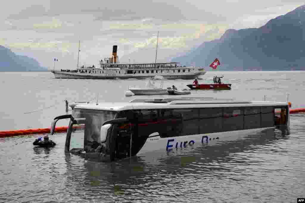 Thợ lặn tìm cách kéo chiếc xe bus bị chìm ở hồ Geneve, Thụy Sĩ. Chiếc xe không có người đang đậu trên đường bỗng nhiên lăn bánh và rơi xuống hồ.