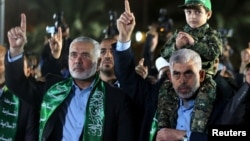 Ismaïl Haniyeh, le chef du Hamas, salue la main levée, lors de sa visite à Gaza, à côté de Yahya Al-Sinwar, chef du parti dans la ville, qui porte son fils Mazen Fuqaha sur les épaules, 27 mars 2017.
