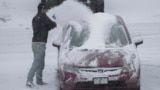 A person dusts snow off of a car during a winter storm, Jan. 5, 2025, in Cincinnati, Ohio. 