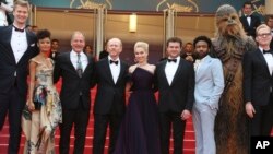 Actors Joonas Suotamo, from left, Thandie Newton, Woody Harrelson, director Ron Howard, actress Emilia Clarke, actor Alden Ehrenreich, actor Donald Glover, a person dressed as the character Chewbacca and actor Paul Bettany pose for photographers upon arrival at the premiere of the film "Solo: A Star Wars Story" at the 71st international film festival, Cannes, southern France, May 15, 2018.