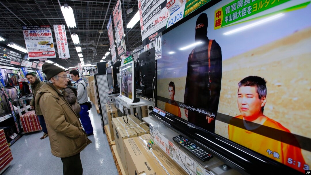 日本東京一名市民在商店內觀看電視新聞報導日本人質事件