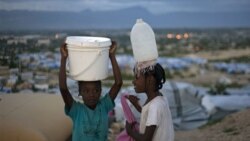 Haitian girls carry water to their family's tent at the Caradeux Camp in Port-au-Prince
