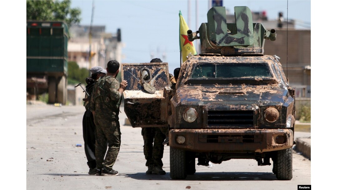 FILE - Kurdish fighters from the People's Protection Units (YPG) stand near a military vehicle in Qamishli city, Syria, April 22, 2016. While Ankara sees the YPG as Kurdish ‘terrorists’ threatening Turkey, Moscow – and Washington – find the group to be a useful partner in fighting Islamic State militants.