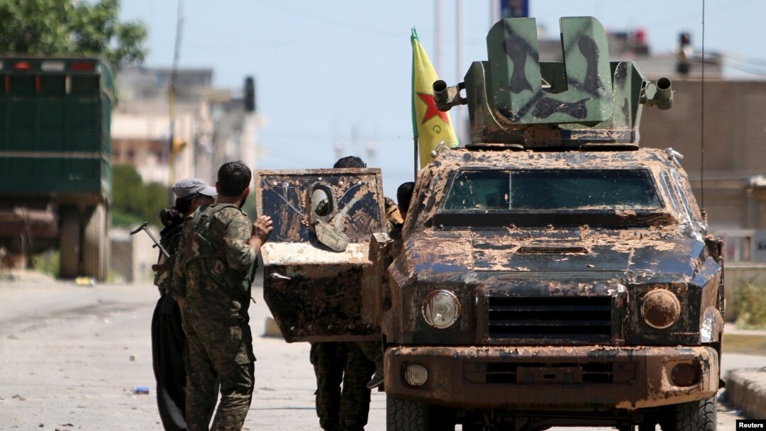 Kurdish fighters from the People's Protection Units (YPG) stand near a military vehilce in the southeast of Qamishli city, Syria, April 22, 2016.