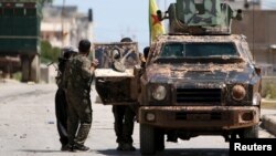 FILE - Kurdish fighters from the People's Protection Units (YPG) stand near a military vehilce in the southeast of Qamishli city, Syria, April 22, 2016. Turkey has accused the U.S. of providing weapons to the rebel force.