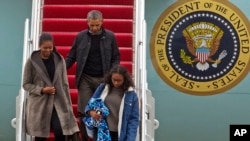 President Barack Obama ditemani ibu negara Michelle Obama dan putri mereka, Sasha, turun dari pesawat Kepresidenan Air Force One setibanya di Pangkalan Angkatan Udara Andrews, Maryland, 2 Januari 2017. (AP Photo/Jose Luis Magana)