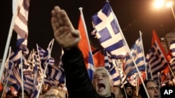 ແຟ້ມຮູບ-ຜູ້ສະໜັບສະໜຸນພັກ Golden Dawn ເຊິ່ງເປັນພັກຂວາຈັດຂອງກຣີສ ຍົກມືຂຶ້ນສະແດງຄວາມເຄົາລົບ ແບບລັກສະນະຂອງນາຊີ ໃນລະຫວ່າງການຊຸມນຸມ ໃນນະຄອນຫຼວງເອເທັນ, ວັນທີ 1 ກຸມພາ 2014.