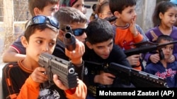 Syrian refugee children play with toy weapons as they imitate Syrian rebels and Syrian troops at a refugee camp in the southern port city of Sidon, Lebanon, Saturday, Oct. 27, 2012. Refugee children often act out their trauma through play.