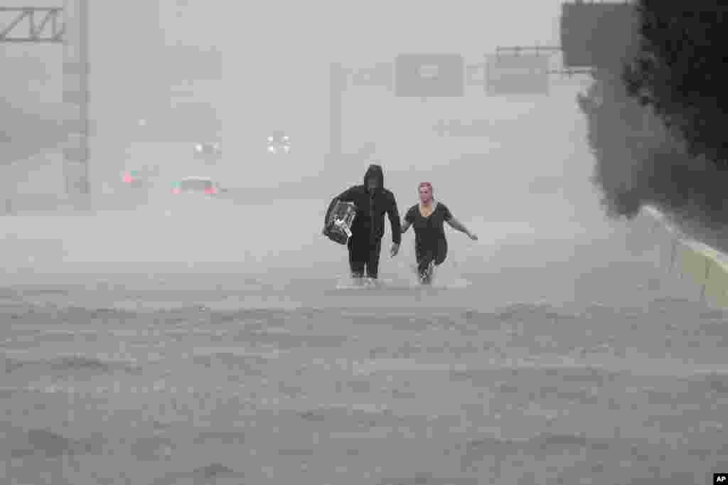 Two people walk down a flooded section of Interstate 610 in floodwaters from Tropical Storm Harvey, Aug. 27, 2017, in Houston, Texas. 