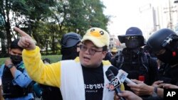 Pemimpin protes Parit "Penguin" Chiwarak mengenakan kostum karakter bebek berwarna kuning, yang telah menjadi simbol perlawanan yang lucu selama unjuk rasa anti-pemerintah di Bangkok, Thailand, saat memberikan keterangan kepada media, Rabu, 25 November 2020.