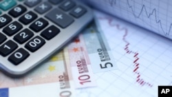 Euro banknotes and a calculator are placed on a currency graph and ticker (File)