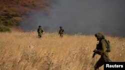 Israeli soldiers patrol next to a smoke from a fire caused by a rocket attack in northern Israel, near the Lebanese border, Aug. 20, 2015. 