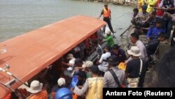 Rescue workers, police and residents prepare to unload the body of a ferry victim in Kolaka, South East Sulawesi, Indonesia, Dec. 20, 2015.