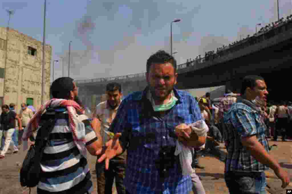 Supporters of Egypt's ousted President Mohammed Morsi react to tear gas during clashes with security forces near the largest sit-in by supporters.