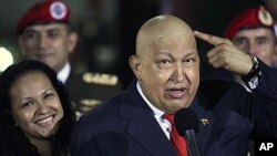 Venezuela's President Hugo Chavez points at his head to show that his hair has started to grow back after his last round of chemotherapy at Miraflores presidential palace in Caracas, Venezuela, October 11, 2011.
