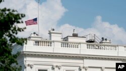 The American flag files at half-staff at the White House, Monday afternoon, Aug. 27, 2018, in Washington.