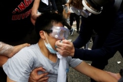 Protesters help a man during a demonstration against a proposed extradition bill where tear gas was fired, in Hong Kong, June 12, 2019.