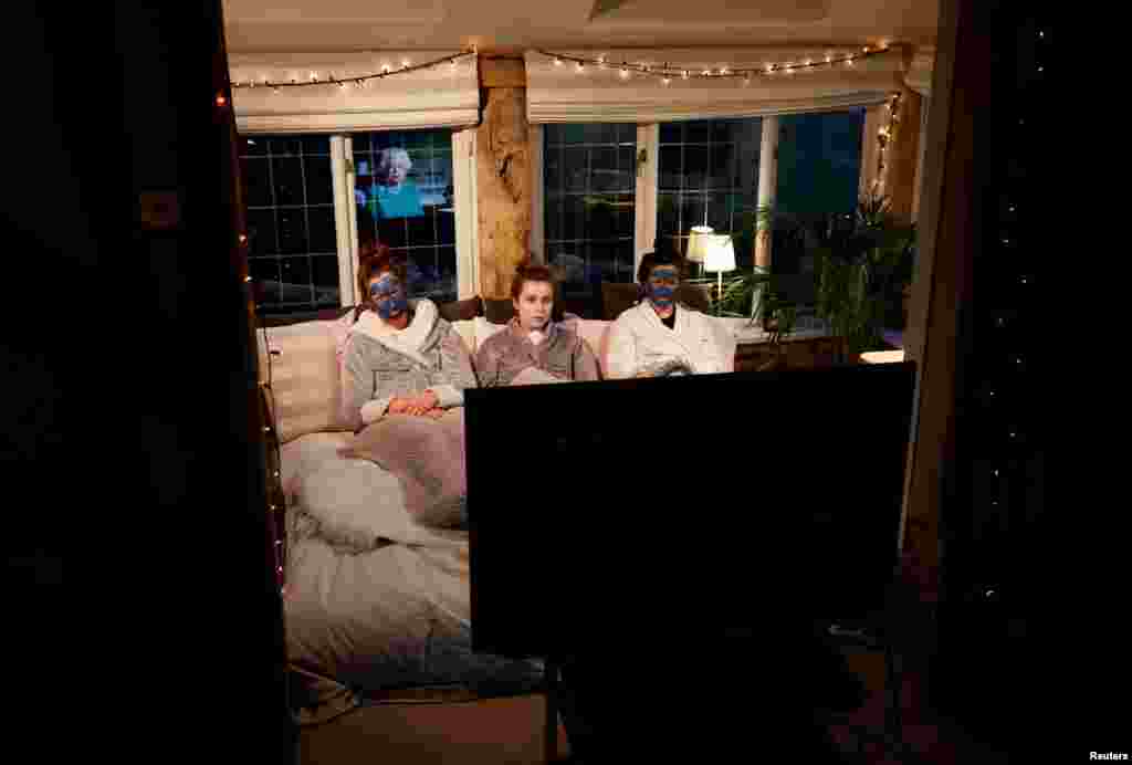 Molly, Emily and Sophie watch Britain&#39;s Queen Elizabeth II during a televised address to the nation at their home in Henton, Britain, April 5, 2020.