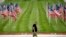 A man walks past a row of flags as he visits a park, Friday, May 15, 2020, in Kansas City, Missouri.