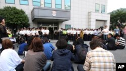 Para anggota keluarga korban tenggelamnya kapal feri Sewol mengikuti jalannya sidang peradilan awak kapal tersebut dari luar gedung pengadilan distrik Gwangju, Korea Selatan (10/6).