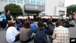 Para keluarga korban kapal Sewol yang tenggelam duduk di depan pengadilan distrik Gwangju di Korea Selatan (10/6). (AP/Ahn Young-joon)