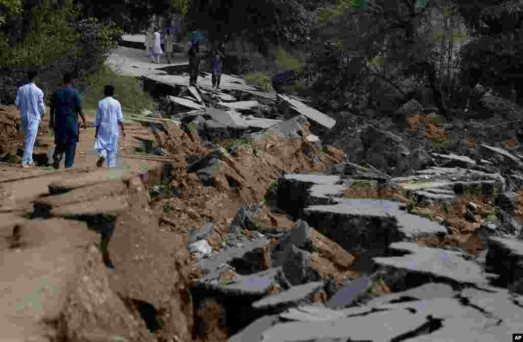 People walk along a damaged section of a road caused by a powerful earthquake in northeast Pakistan. The 5.8-magnitude quake struck Pakistan-held Kashmir and other places, killing 25 people and injuring 700.