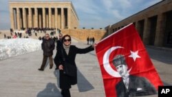 People hold national flags with posters of the founder of modern Turkey Kemal Ataturk as they visit his mausoleum in Ankara, Turkey, February 5, 2012.