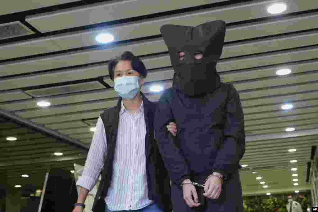 A hooded suspect is accompanied by a police officer to search evidence at office in Hong Kong.&nbsp;National security police arrested five people from a trade union of the General Association of Hong Kong Speech Therapists on suspicion of conspiring to publish and distribute seditious material.&nbsp;