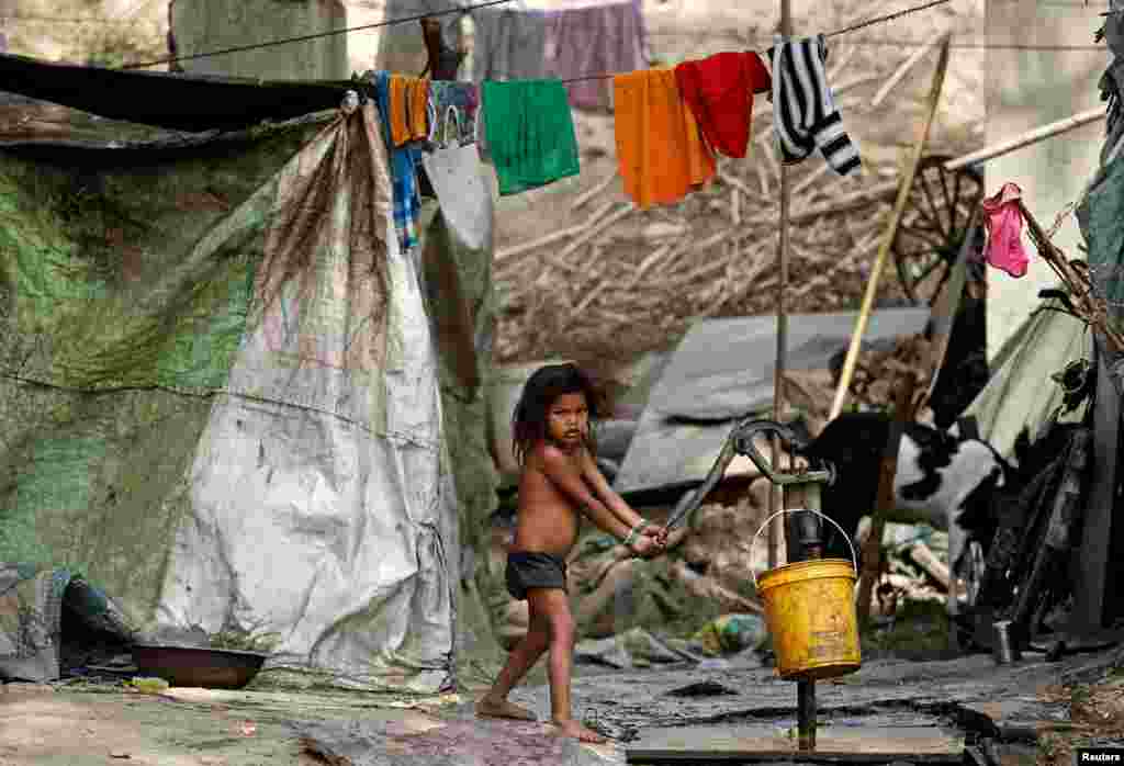 A child uses a hand pump to extract water on the banks of the river Yamuna in New Delhi, India.