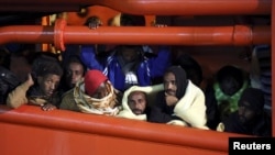 Migrants wait to disembark from a tug boat in the Sicilian harbor of Pozzallo, southern Italy, May 4, 2015.