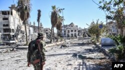 FILE - A member of the Syrian Democratic Forces (SDF) walks through a heavily damaged street leading to an Armenian church in Raqqa, Syria, Oct. 18, 2017.