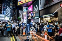 黃之鋒在香港銅鑼灣街頭講話，當時附近的維多利亞公園正在舉行當局以新冠疫情為由禁止的紀念六四燭光集會。（2020年6月4日）