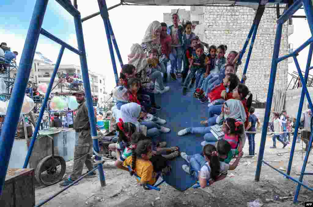 Children play at a makeshift amusement park as they celebrate the Eid al-Fitr feast in Syria&#39;s northwestern city of Idlib.