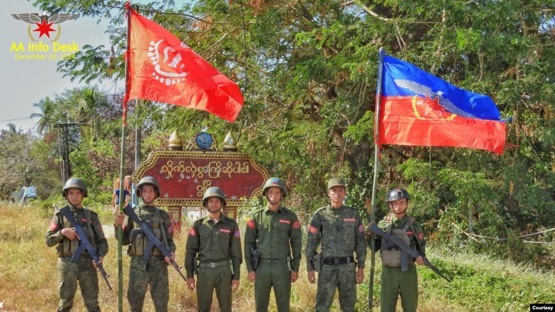 FILE - A photo released by the Arakan Army shows its members posing in front of the Gwa town signboard at the entrance gate, following their capture of Gwa Township in southern Rakhine State, Myanmar, on Dec. 29, 2024.