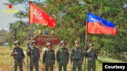 FILE - A photo released by the Arakan Army shows its members posing in front of the Gwa town signboard at the entrance gate, following their capture of Gwa Township in southern Rakhine State, Myanmar, on Dec. 29, 2024.