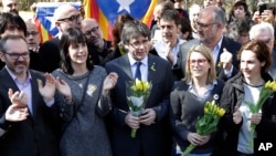 Mantan pemimpin Catalan, Carles Puigdemont, (tengah) memegang seikat bunga saat dia dan pendukungnya bernyanyi setelah konferensi pers di Berlin, Jerman, Sabtu, 7 April 2018.