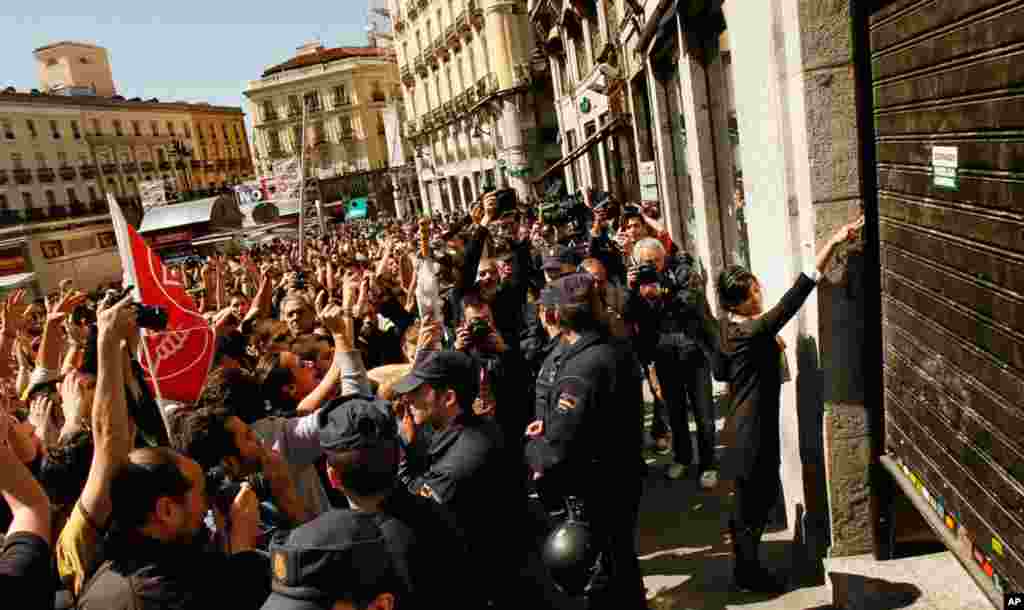 A retail employee closes down her shop under protestors' pressure in Madrid, Spain. March 29, 2012. The one-day trade union-sponsored general strike is to protest austerity measures permitting less costly worker hirings and firings. (AP)
