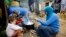 FILE - A Syrian refugee woman with her children prepares food near her tent in a camp for Syrians who fled their country’s civil war, in the Chouf mountain town of Ketermaya, Lebanon. 