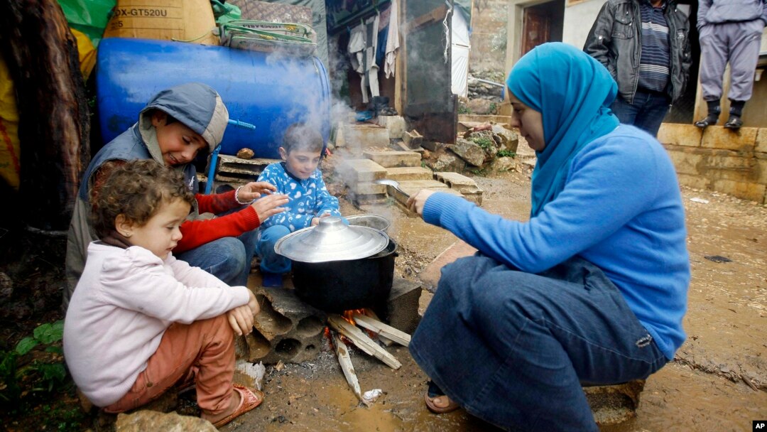 Anak-anak pengungsi Suriah dan ibunya sedang mempersiapkan makanan dekat tenda mereka di kamp pengungsi Ketermaya, Lebanon.(AP/Mohammed Zaatari) 