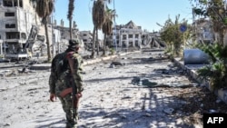 FILE - A member of the Syrian Democratic Forces (SDF) walks through a heavily damaged street leading to an Armenian church in Raqqa, Syria, Oct. 18, 2017.