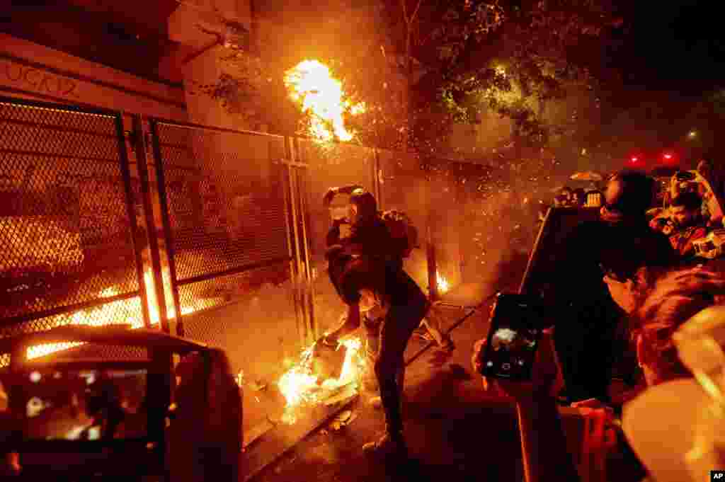 Protesters throw flaming debris over a fence at the Mark O. Hatfield United States Courthouse on Wednesday, July 22, 2020, in Portland, Oregon.
