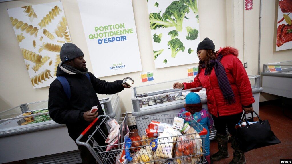 Les demandeurs d'asile nigérians Abimbola Ogunyemi, à gauche, et Esther Ogunyemi en compagnie de leur fille Nifemi dans un magasin d'alimentation de Montréal, Québec, Canada, le 13 février 2018.