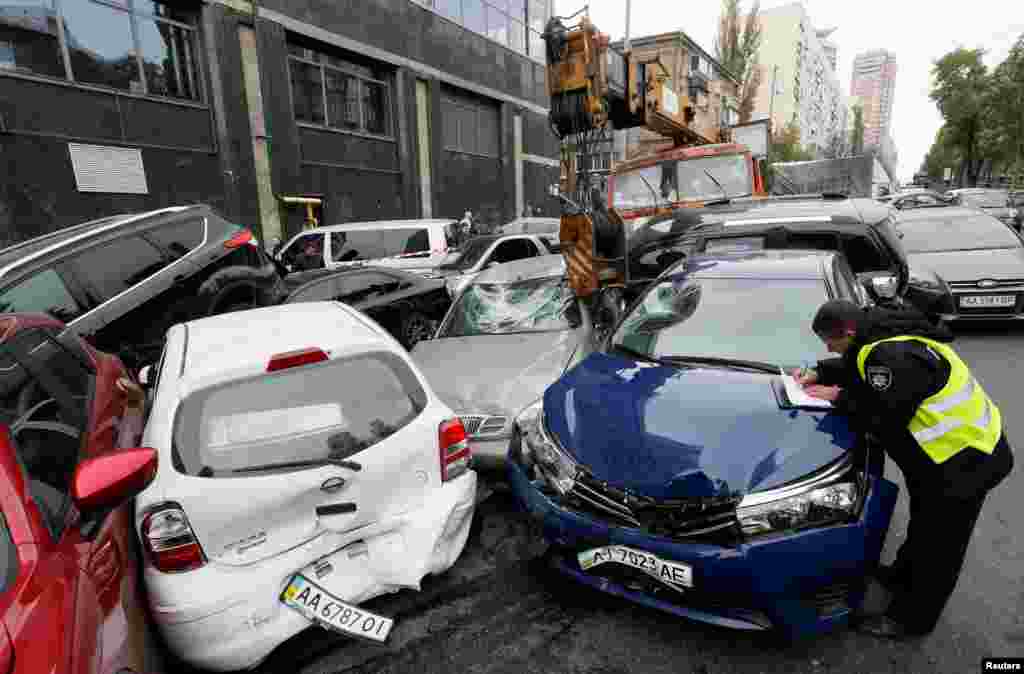 A police officer works at the site of a road accident after a mobile crane crashed into passenger vehicles in Kyiv, Ukraine.