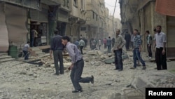 Residents stand at a site hit by what activists said were airstrikes by forces loyal to Syria's President Bashar al-Assad in Arbeen town, outside Damascus, May 27, 2015.